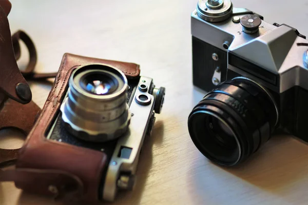 Due vecchie fotocamere vintage su un tavolo marrone chiaro. Uno in pelle retrò marrone custodia titolare — Foto Stock