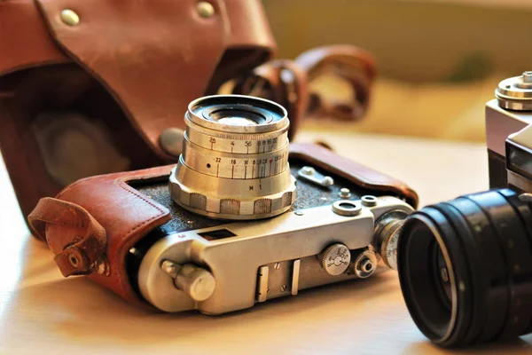 Due vecchie fotocamere vintage su un tavolo marrone chiaro. Uno in pelle retrò marrone custodia titolare — Foto Stock