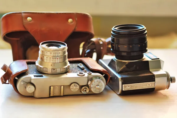 Due vecchie fotocamere vintage su un tavolo marrone chiaro. Uno in pelle retrò marrone custodia titolare — Foto Stock