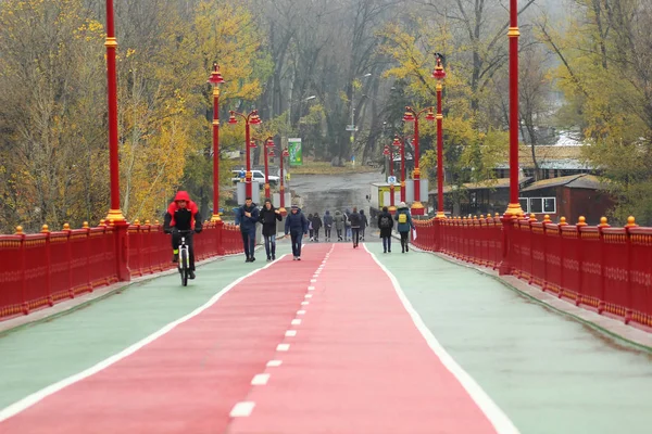 Menschen, die an einem regnerischen nebligen Tag auf der Fußgängerbrücke in der Innenstadt von Kyiv spazieren und reiten, unmittelbar nachdem die Rekonstruktion abgeschlossen ist — Stockfoto