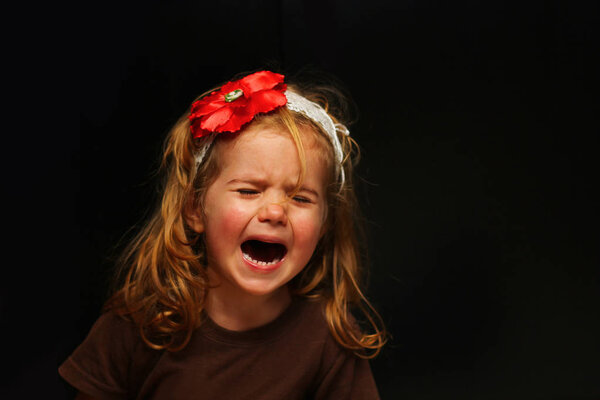 Upset little girl crying out load, portrait isolated on black