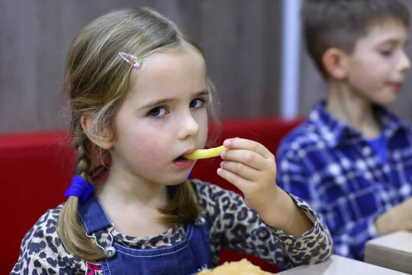Portrait of a caucasian four year old girl eating french fries in a cafe