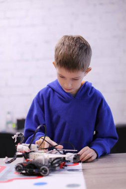 Okul dersinde robot yapan bir çocuğun portresi. Robotik, Kök