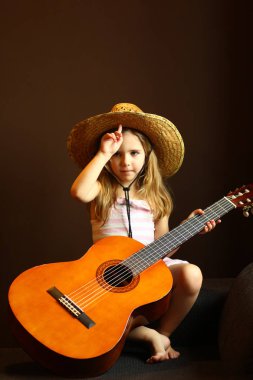 Kafkasyalı küçük bir kızın portresi hasır şapka takıyor ve gitar tutuyor.