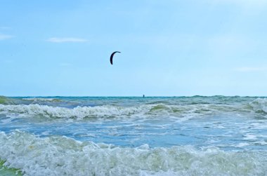 Gökyüzünde bir gün batımı bir arka plan karşı bir paraplan üzerinde bir erkek yamaç paraşütü silueti.