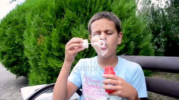 Heureux adolescent soufflant des bulles de savon dans le parc de printemps . — Video