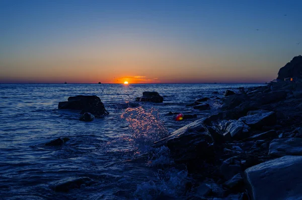Puesta de sol brillante bajo el mar con salpicaduras de olas . — Foto de Stock