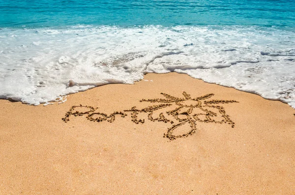 Hand written text Portugal and sun symbol on the golden beach sand with coming waves