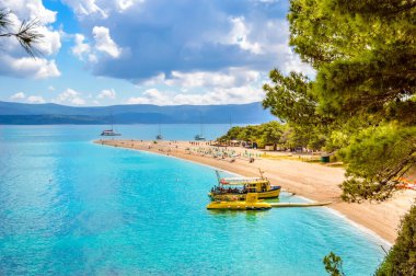 Zlatni Rat beach or Golden Horn in Bol town on Brac Island, Croatia. Scenic pebble beach with pine trees and turquoise sea water