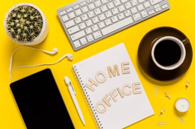 Tablet, klavye, kulaklık, kahve fincanı, not defteri, kalem ve kaktüsle modern çalışma alanı. Mektuplarda İçişleri Bakanlığı yazıyor. Sarı arkaplanda üst görünüm