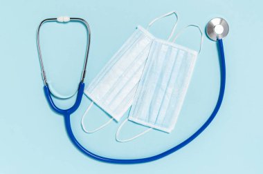 Stetoskop ve mavi arka planda tıbbi cerrahi maskeler. Coronavirus koruması. Covid-19 'u önlemek için hijyen önlemleri