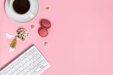 Klavyeli kadın çalışma alanı, bir fincan sade kahve, iki badem kurabiyesi ve pembe arka planda bir demet papatya çiçeği. Merkez ofis, serbest çalışma ya da uzaktan çalışma konsepti. Kopyalama alanı olan düz
