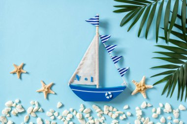 Yelkenli teknesi, palmiye yaprakları ve mavi arka planda deniz yıldızları olan deniz kompozisyonu. Yaz tatili ve turizm, deniz seyahati nesneleriyle bezenmiş.