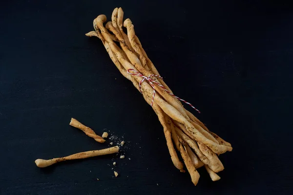 La colación tradicional italiana, el pan - grissini. En una mesa de piedra oscura . — Foto de Stock