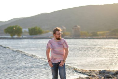 Genç adam sahilde duruyor.