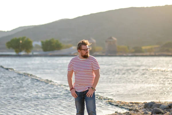 Genç adam sahilde duruyor.