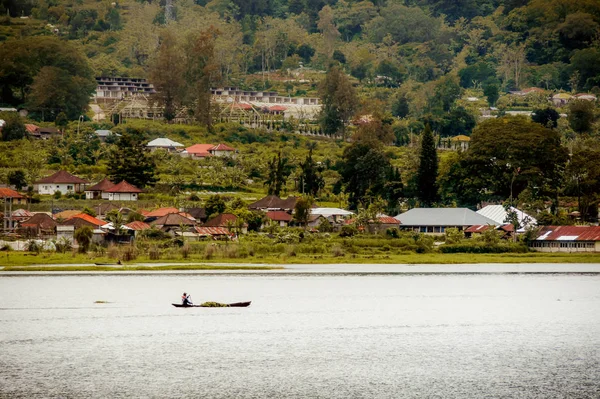 local resident man on boat with algae floating along shore of bay