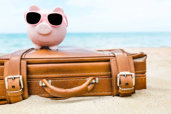 Piggy bank with case on sea beach — Stock Photo, Image