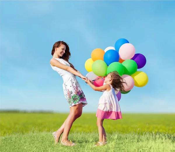 Mãe com filha segurando balões coloridos — Fotografia de Stock