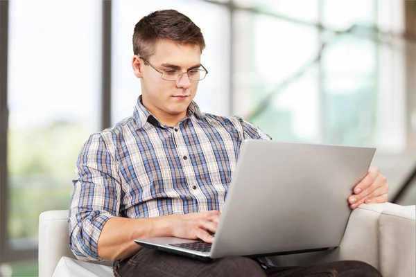 Homem relaxante no sofá com um laptop — Fotografia de Stock