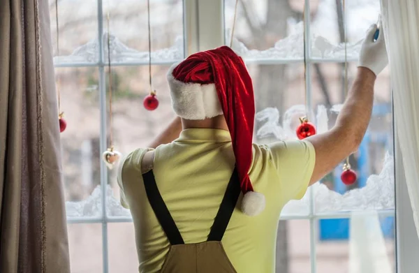 Man in KERSTMUTS versieren venster — Stockfoto