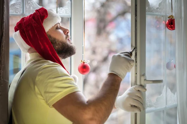 Homme dans le chapeau du Père Noël réparation fenêtre — Photo