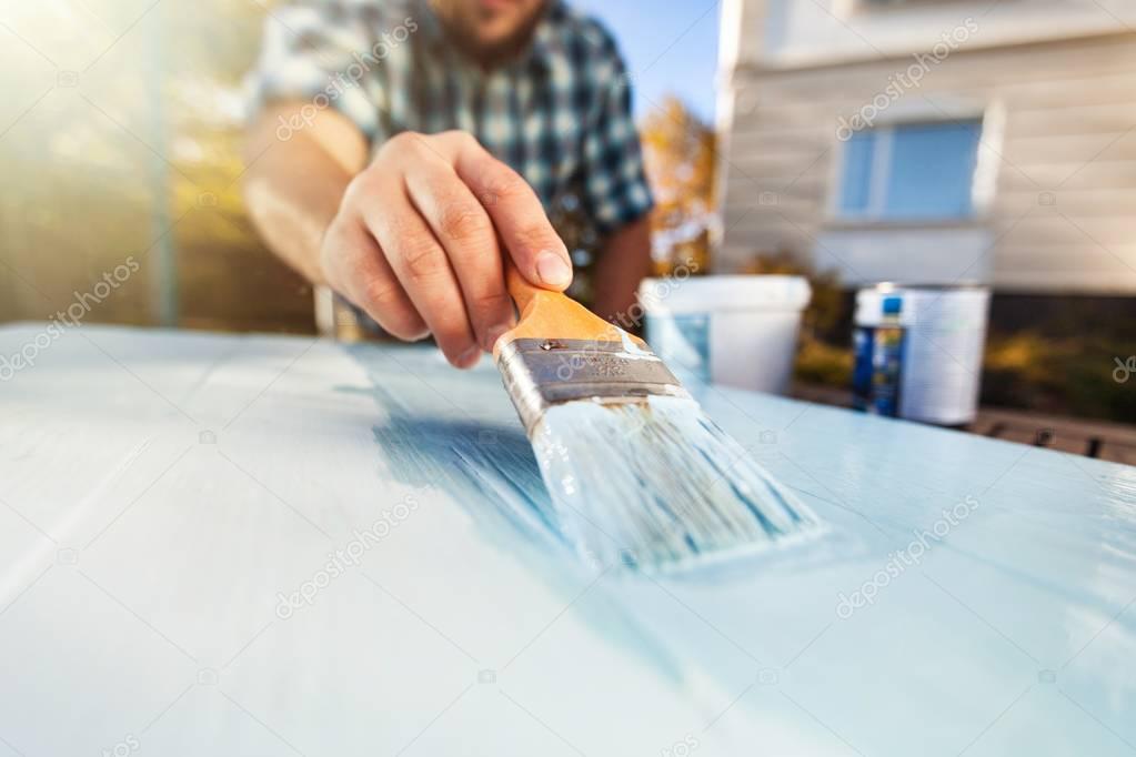 man with paintbrush  painting on the wooden board