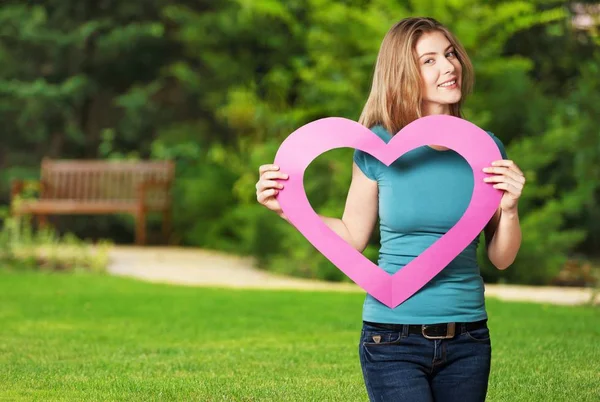 Meisje bedrijf roze papieren hart — Stockfoto