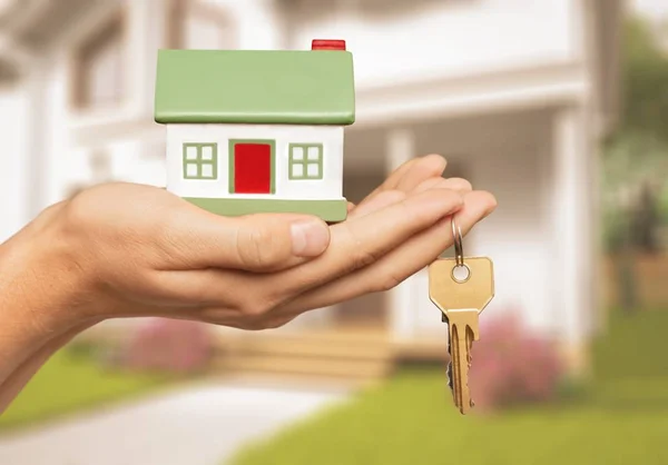 Mão segurando modelo de casa — Fotografia de Stock