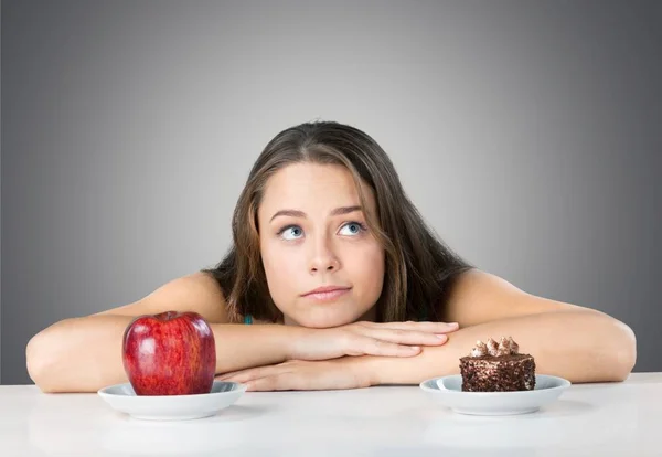 Frau trifft Wahl zwischen Apfel und Kuchen — Stockfoto