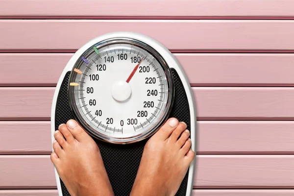 Woman legs on black scales — Stock Photo, Image