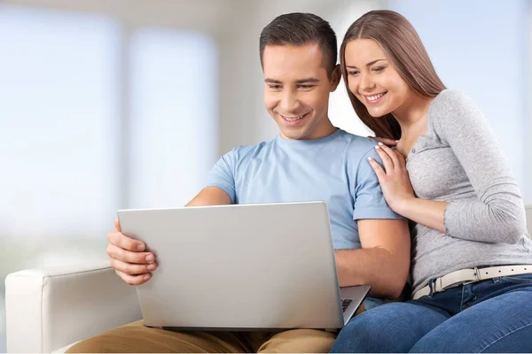 Lachende paar met de laptop op de Bank — Stockfoto