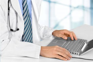 Doctor working on laptop computer clipart