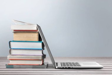 Dizüstü bilgisayar ile kitap yığını