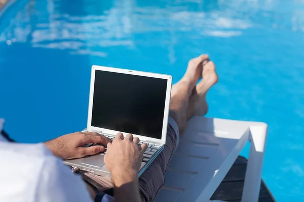 Homem usando laptop perto da piscina — Fotografia de Stock
