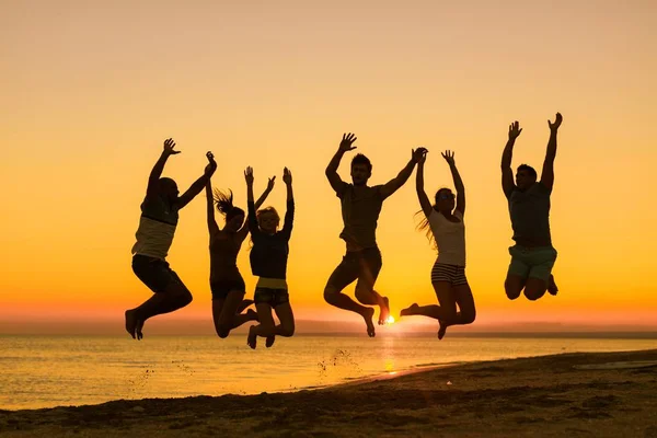 Freunde springen am Strand — Stockfoto