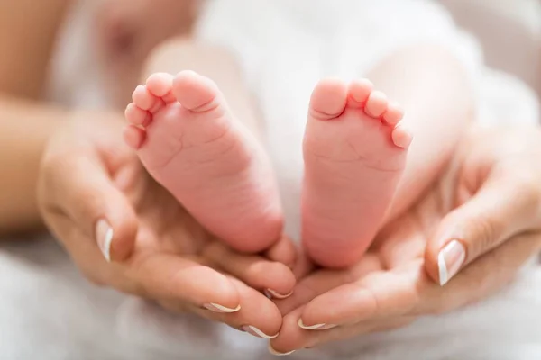 Детские ножки в руках матери — стоковое фото