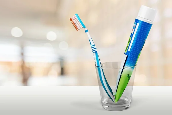 Toothbrush and toothpaste in glass — Stock Photo, Image