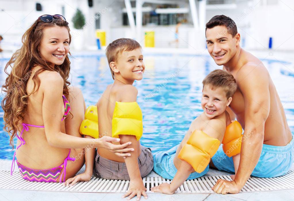 Happy family playing in swimming pool. 