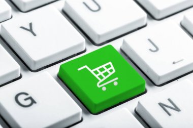 Online internet kavramı ile tek bir büyük yeşil anahtar ile bir alışveriş sepeti simgesi beyaz bilgisayar klavye açılı görünümü kadar yakın ile alışveriş