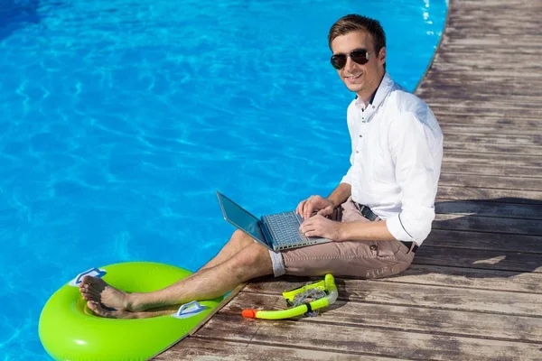 Jovem empresário com laptop na piscina — Fotografia de Stock