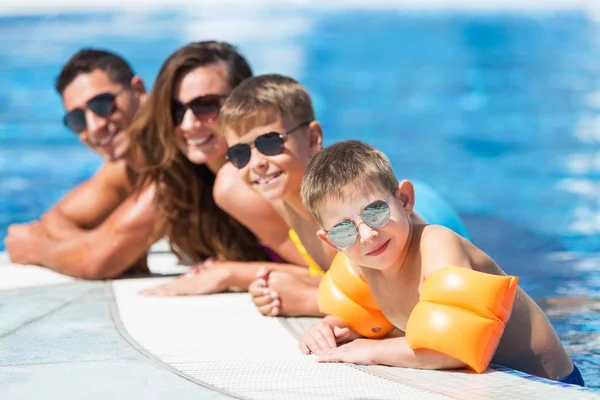 Familia feliz jugando en la piscina — Foto de Stock