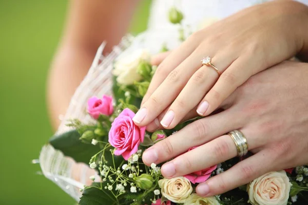Mãos de pessoas com anéis e flores — Fotografia de Stock