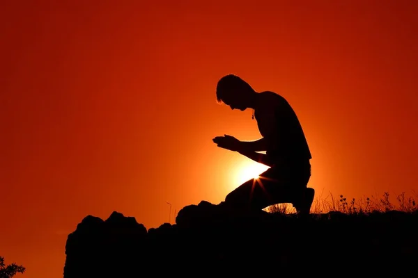 Silueta člověka modlit v západu slunce — Stock fotografie