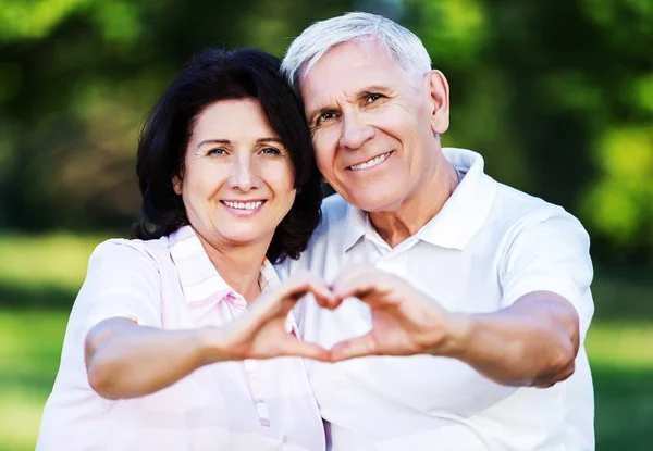 Anziani coppia mostrando il segno del cuore — Foto Stock