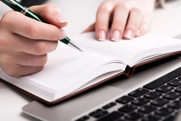 Mãos segurando caneta e escrever em notebook — Fotografia de Stock