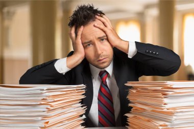 Bir yığın evrakı olan genç iş adamı.