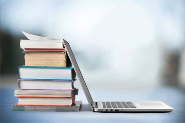 Dizüstü bilgisayar ile kitap yığını