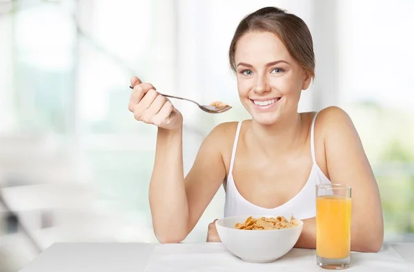 Young woman eating cornflakes — Stock Photo, Image