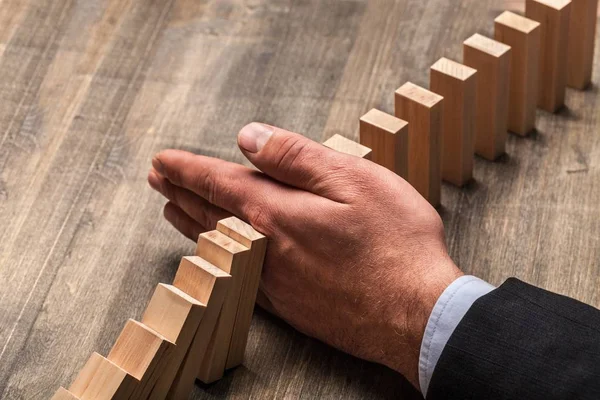 Hand stoppa fallande dominos — Stockfoto